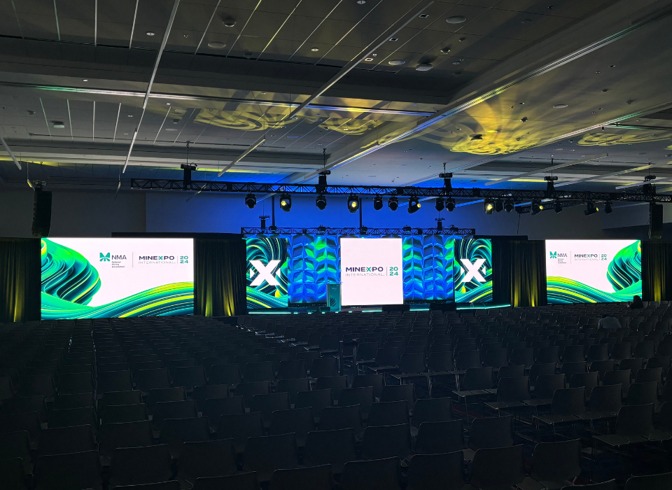 Three L E D Screens On Stage Sporting N M A Logos And Green Branding